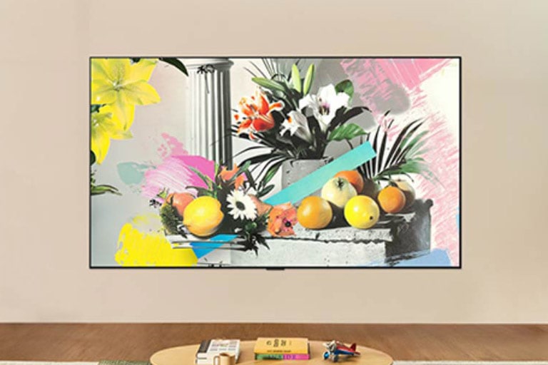 LG ART TV er veggmontert i et lyst rom, og viser et fargerikt blomster- og fruktkunstverk i gallerimodus mens lysstyrkekontrollen justerer for optimal visning i all slags lys.