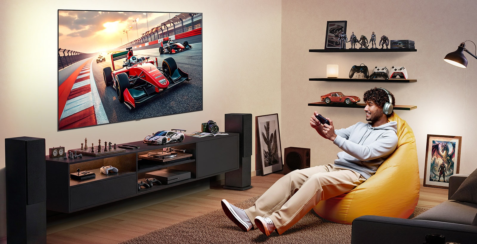 LG TV med storskjerm er veggmontert i et spillrom med gamingutstyr som dekorative elementer, der en stor skjerm viser en høyhastighets racingscene mens en person slapper av i en saccosekk og nyter oppslukende underholdning.