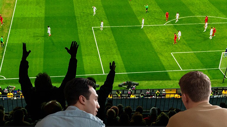 Folk som ser på en sportskamp på TV i stua med en ultrastor TV-skjerm