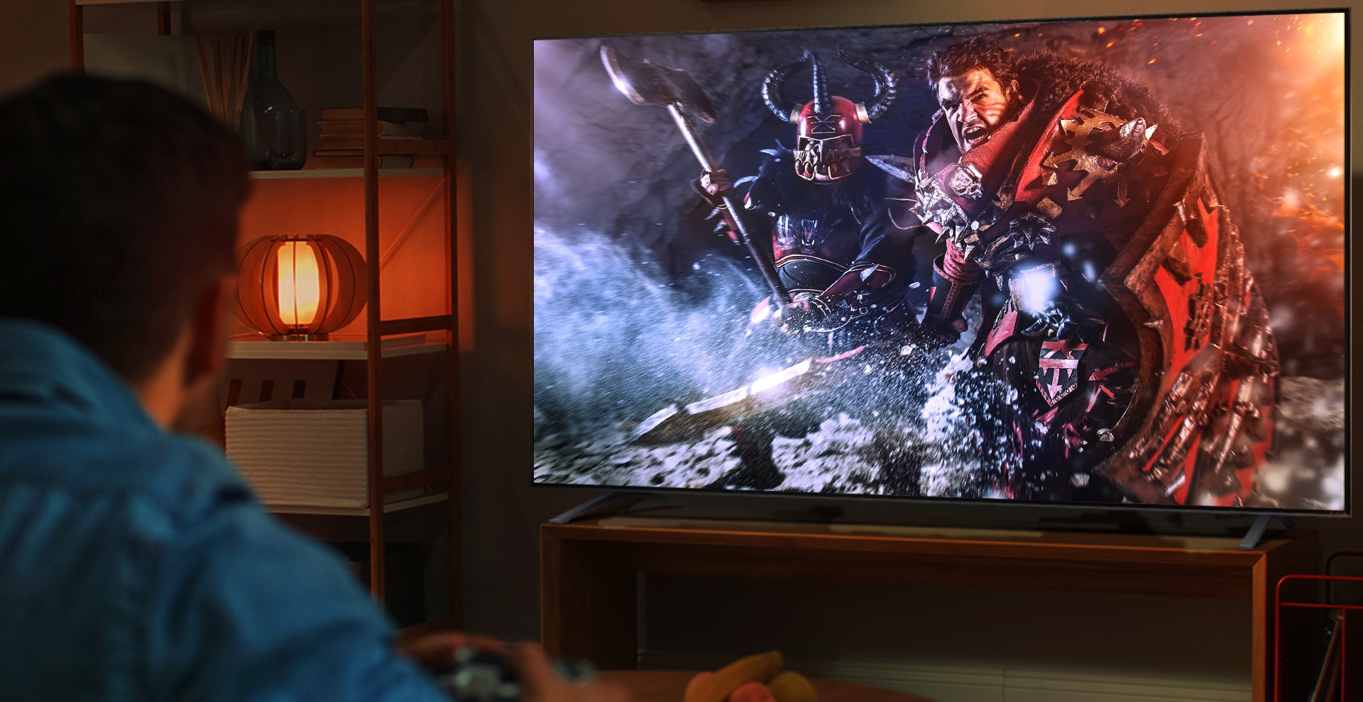 En mann sitter på en sofa i et mørkt rom og spiller et RPG-spill på en stor TV.