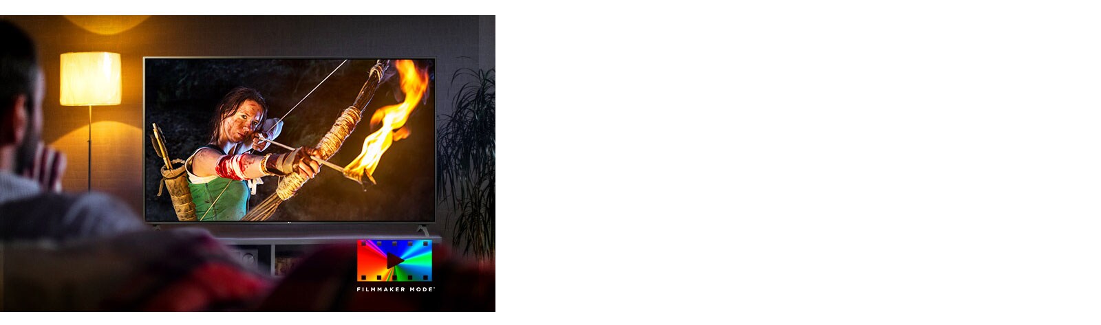 A man is sitting on a couch watching an action movie. The girl on the TV has a fully drawn bow and arrow.