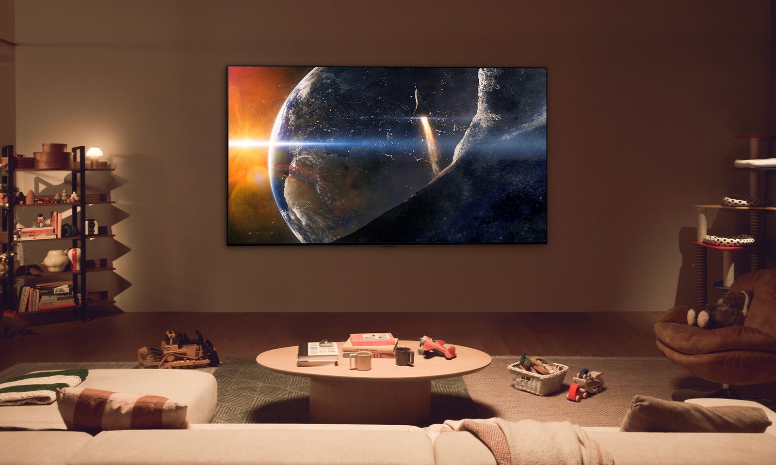 An image of a family sat on the floor of a low-lit living room by a small table, looking up at an LG TV mounted on the wall showing the Earth from space.