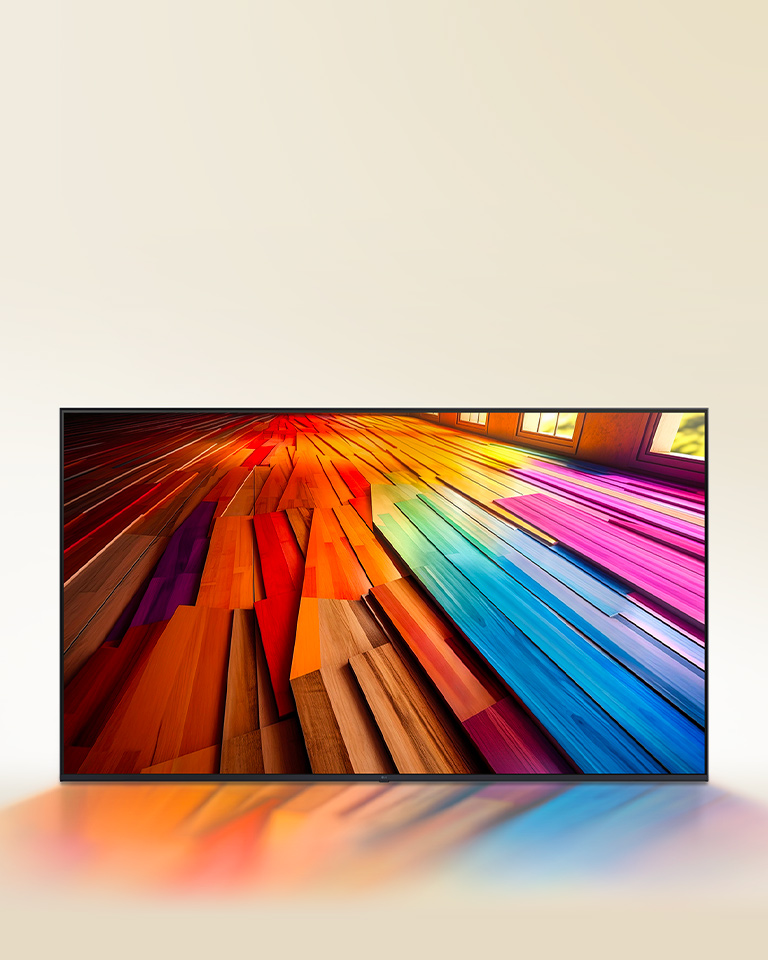 An image of a vibrantly colored, long stretch of hardwood flooring is displayed on an LG TV. The colors lightly reflect on the space below the TV.