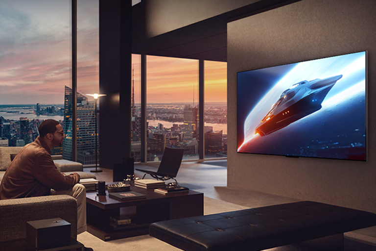 Living room with a TV mounted on the wall. Screen shows a high quality image of a whale leaping out of the water.