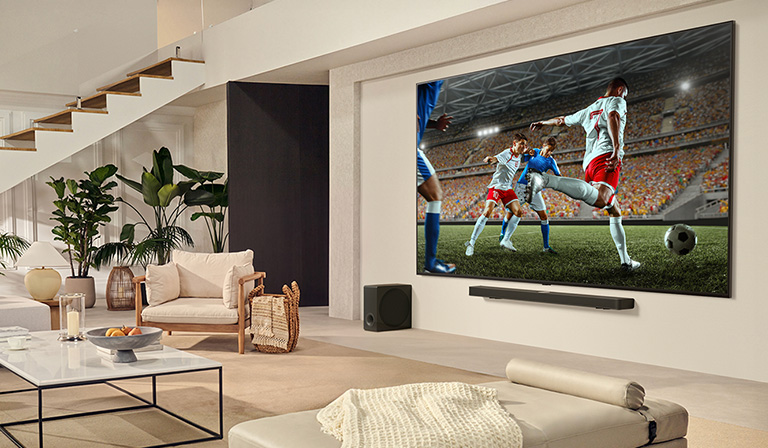 A family is gathered around their LG Ultra Big TV watching an exciting soccer match on the huge screen. 