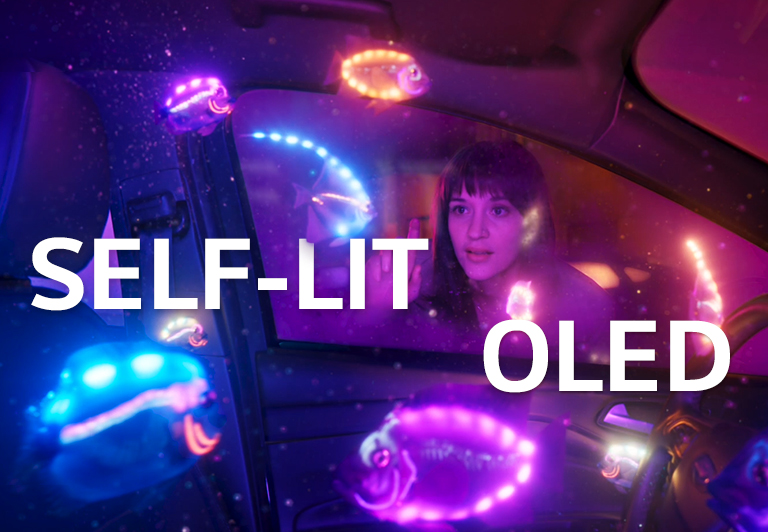 A woman watching inside of a car filled with shiny fish in multiple colors. And, there is the text of ‘SELF-LIT OLED’ in the middle of the image.