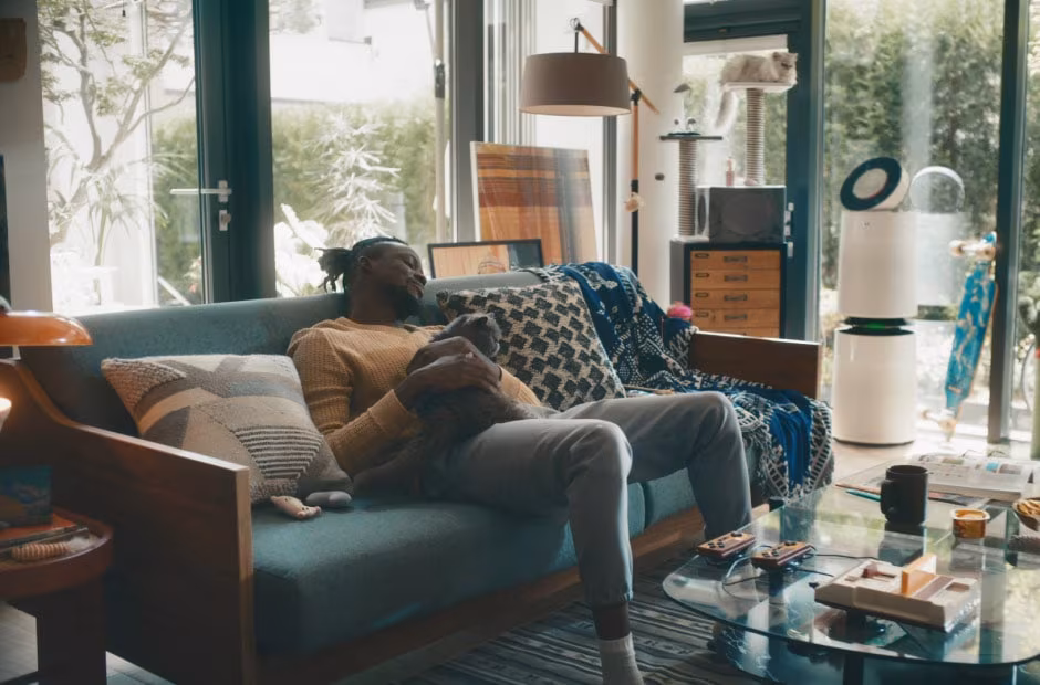 LG ThinQ ON AI voice assistant device sits on a coffee table in a smart living room, with a glowing LED ring.