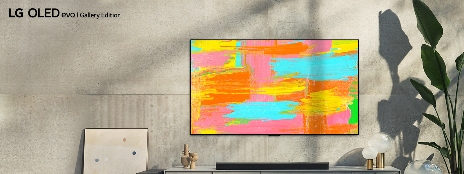 An image of LG OLED G2 hung on the wall of a minimalist gray room with a bright and vibrant abstract artwork displayed on the screen. The words "Make life a masterpiece" are displayed over the image.