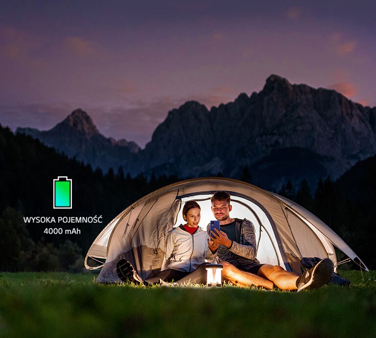 Mężczyzna i kobieta oglądają smartfona w namiocie w środku nocy.