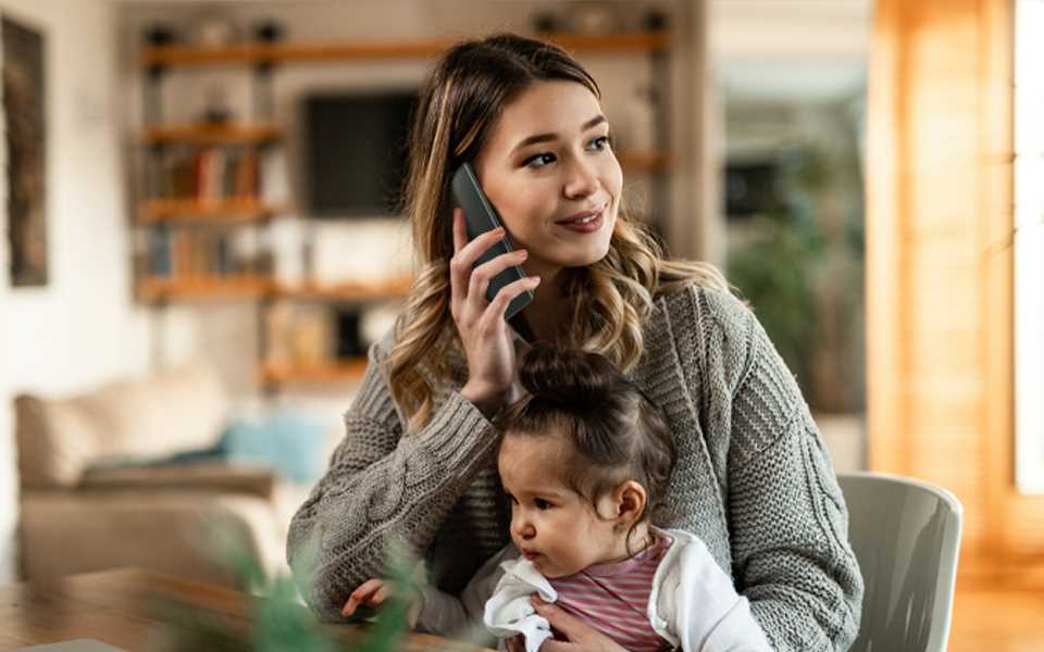 A woman talking on her LG WING whilst holding a child