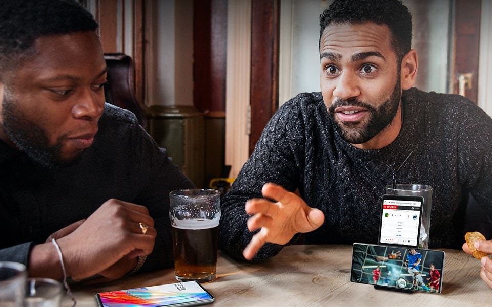 A group of friends watching football on an LG WING at a pub