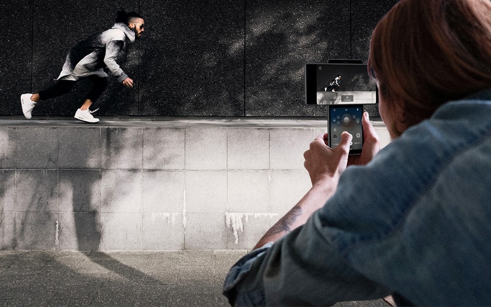 A woman recording a man running with the LG WING's gimbal motion camera feature