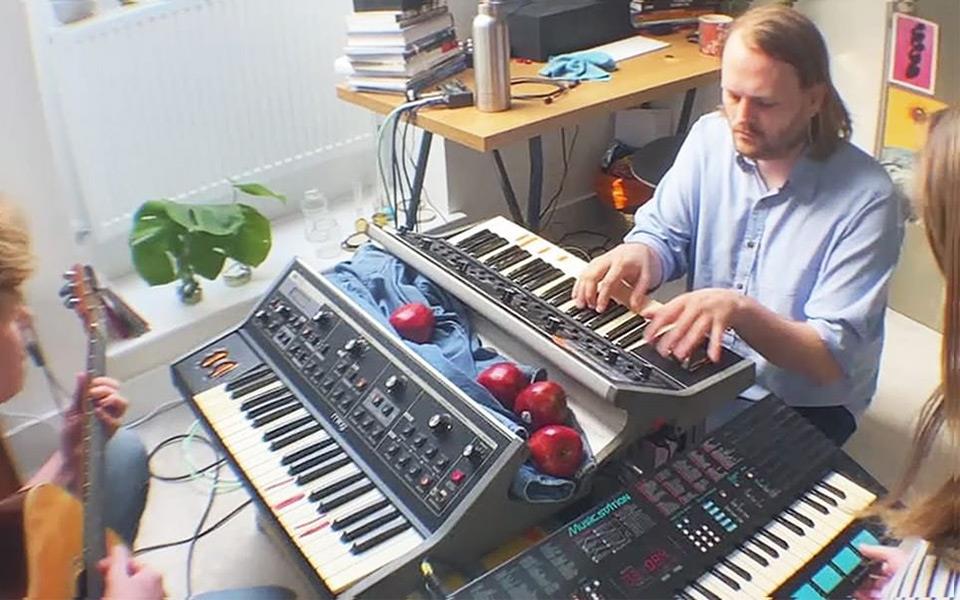 A man playing one of two keyboards in a room. 