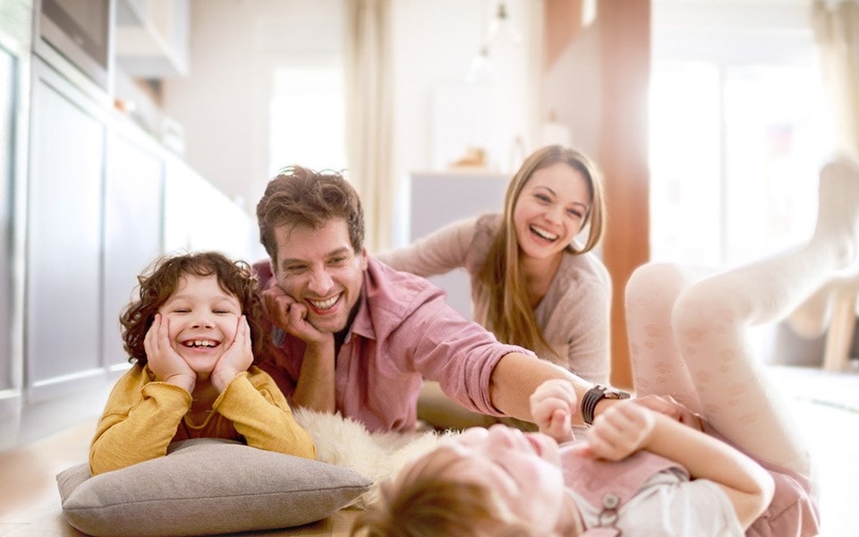 A family laying on the floor with the father tickling one of the children.