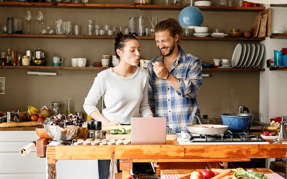 A man and woman cooking in a kitchen together.