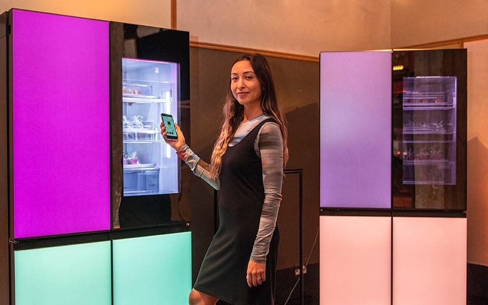 A woman demonstrates the colour-changing panels of an LG MoodUP smart refrigerator