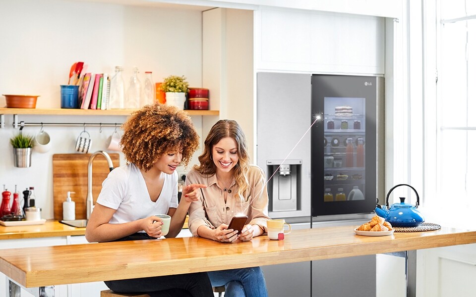 Two women connect their InstaView smart refrigerator with the LG ThinQ app.