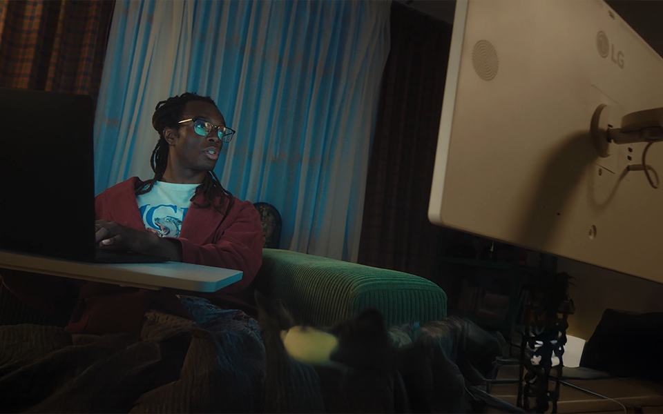 A man working on a sofa while looking at an LG 360 monitor.