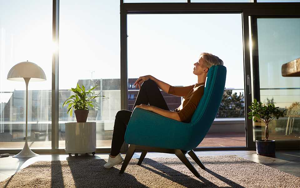 A woman relaxing in an armchair and admiring the view from her home