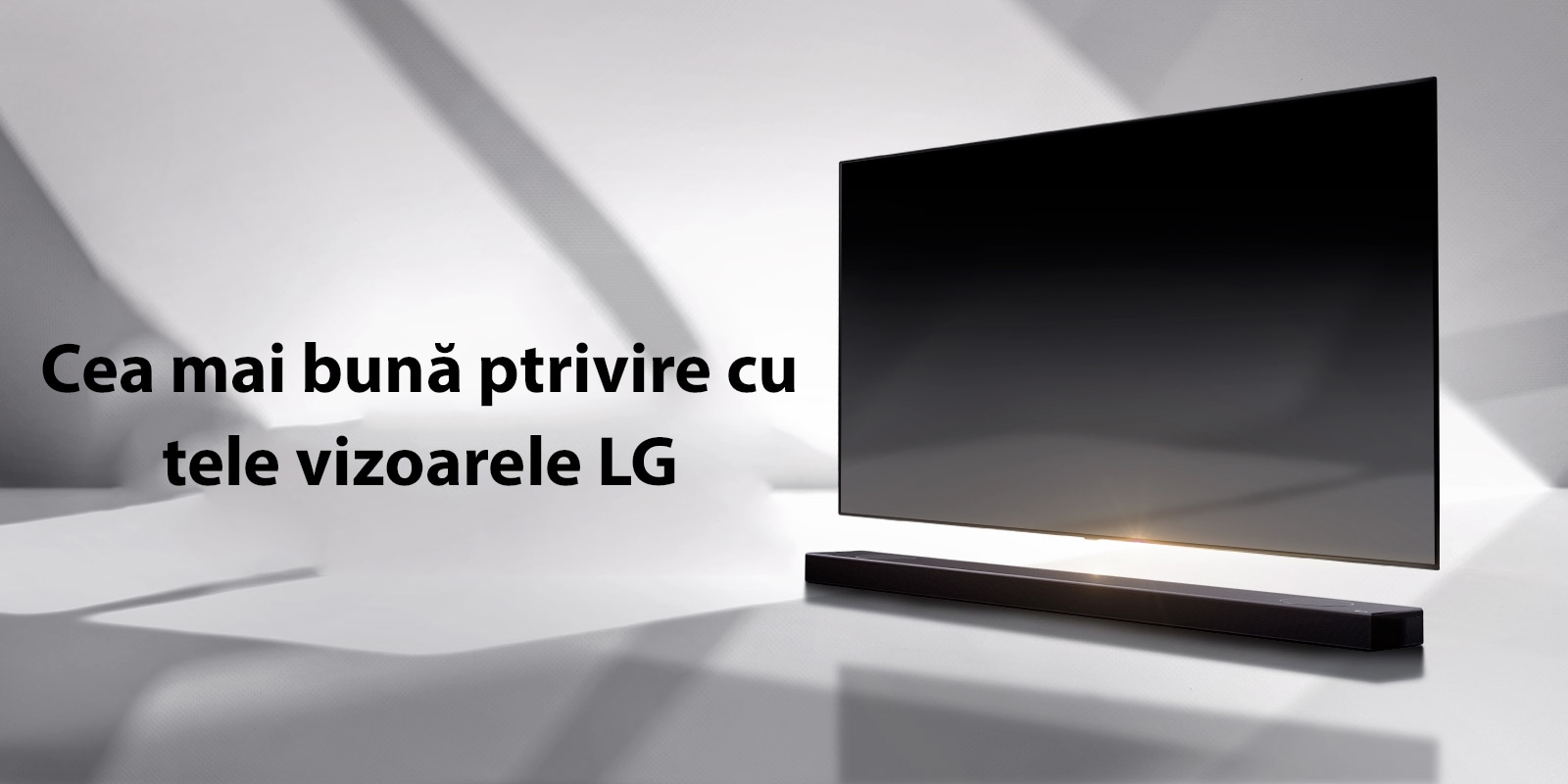 O bară de sunet și un televizor sunt plasate pe o podea albă și există o umbră care vine din exterior chiar în spate.