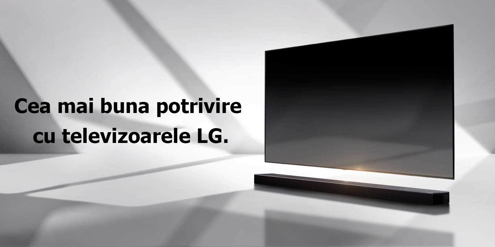 O bară de sunet și un televizor sunt plasate pe o podea albă și există o umbră care vine din exterior chiar în spate.