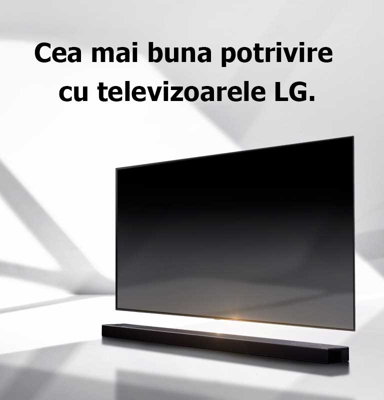 O bară de sunet și un televizor sunt plasate pe o podea albă și există o umbră care vine din exterior chiar în spate.