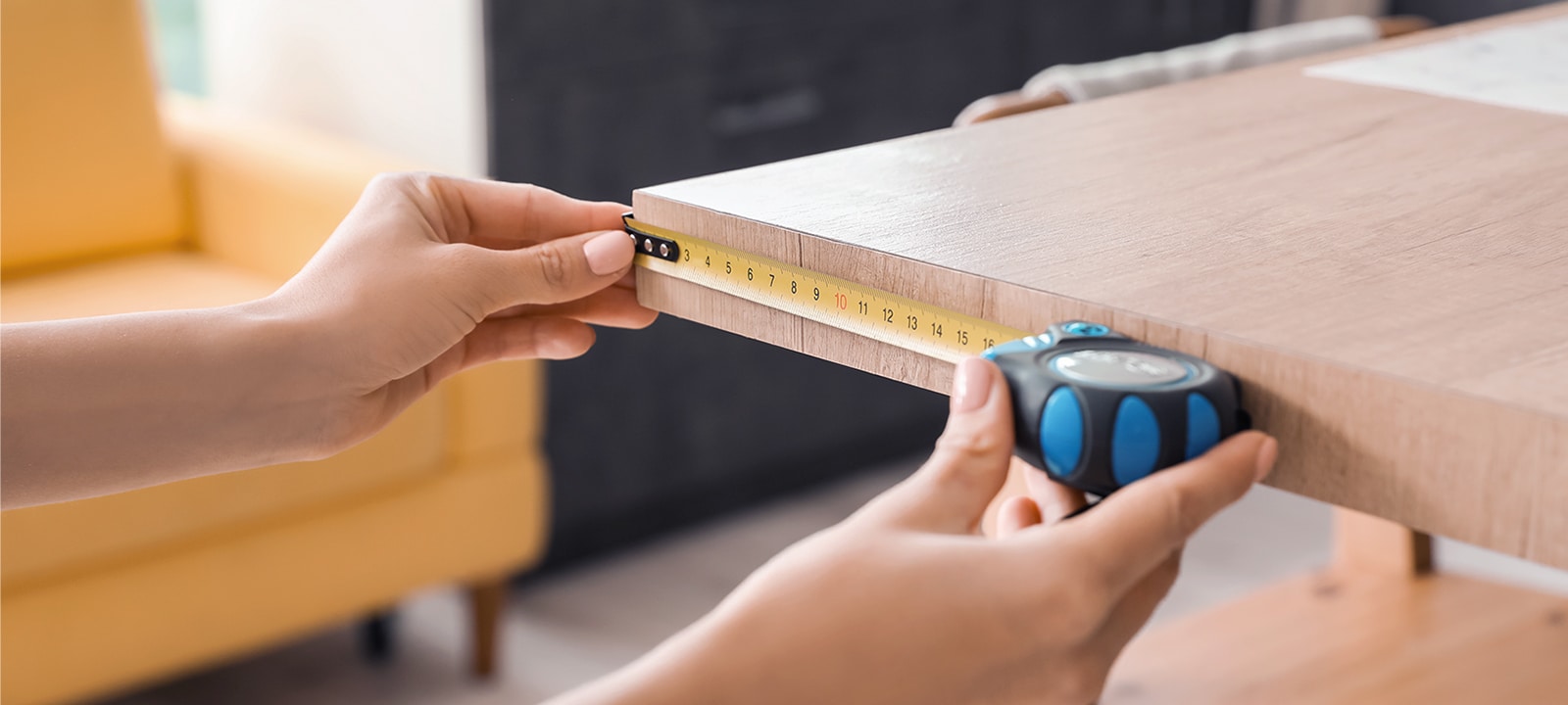 Cineva măsoară dimensiunile mobilierului folosind un ruleta de măsurat.