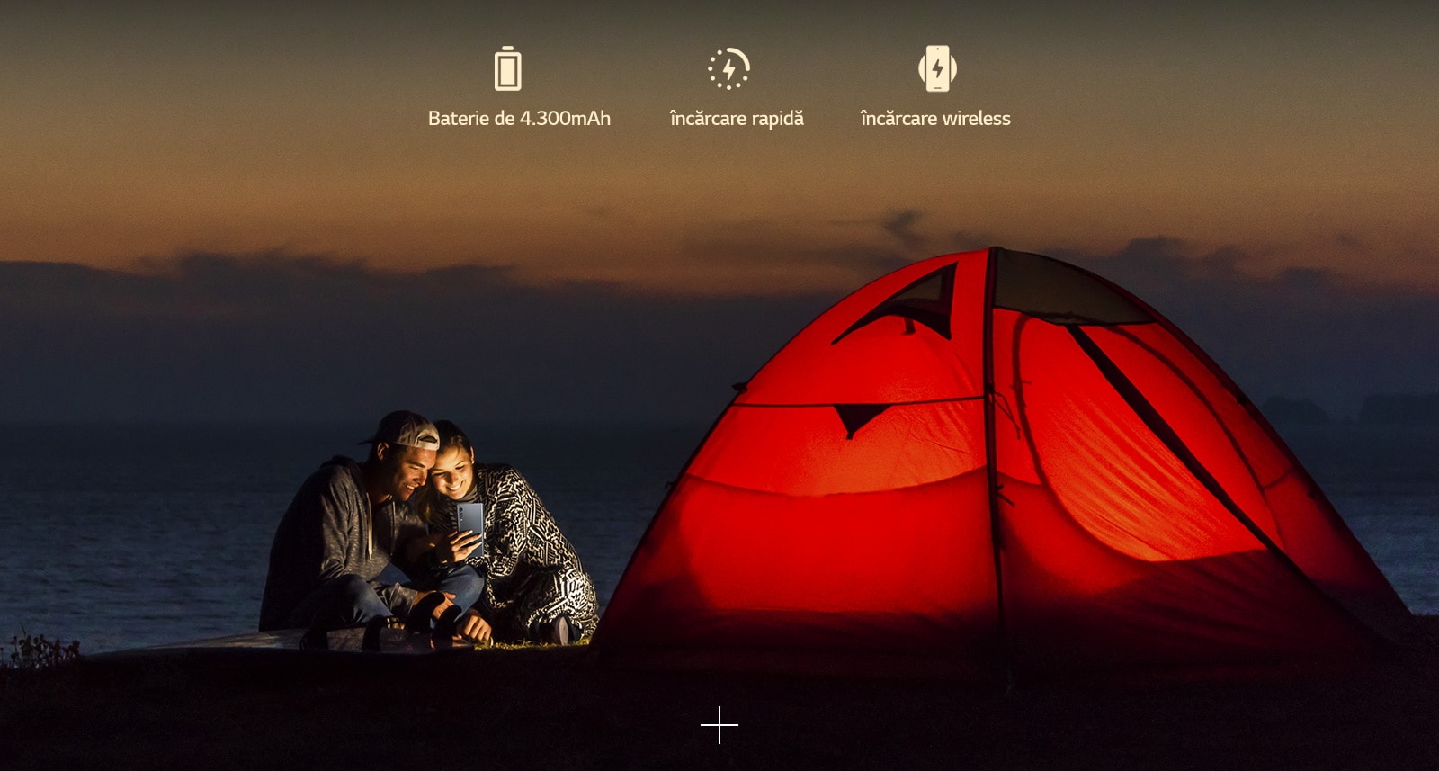 Un cuplu în fața unui cort, pe timp de noapte