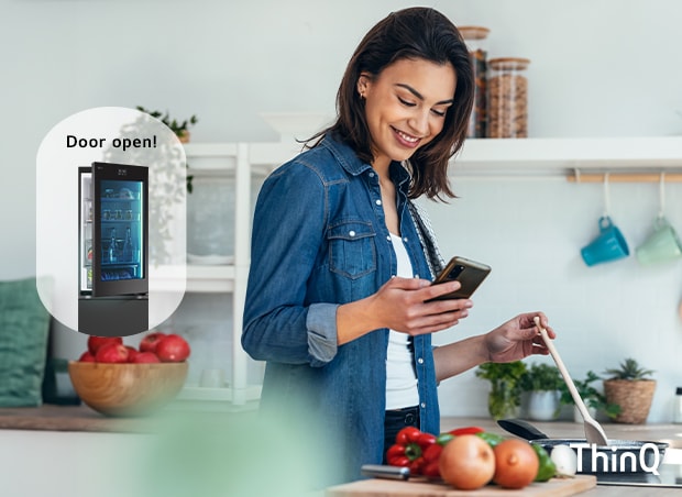 O imagine cu o femeie care gătește, uitându-se la telefon, 