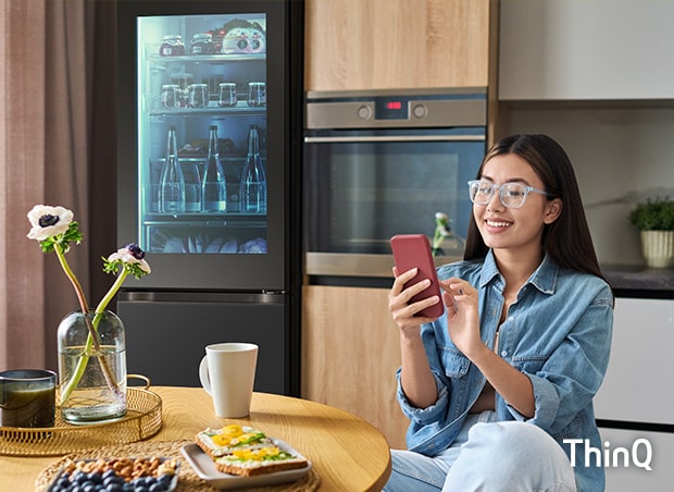 O imagine cu o femeie care atinge telefonul în bucătărie.