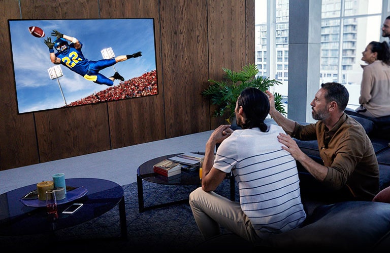 Oameni care urmăresc meciul lui Tottenham la televizor în camera de zi