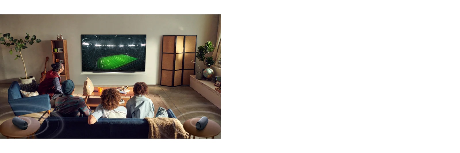 Oameni care urmăresc un joc sportiv la televizor în camera de zi, cu difuzoare Bluetooth în spate