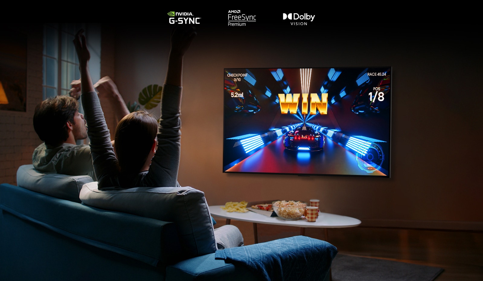 Doua persoane stau pe o canapea si se joaca un joc de curse cu o unitate de comanda si televizorul LG OLED G2 intr-o sufragerie