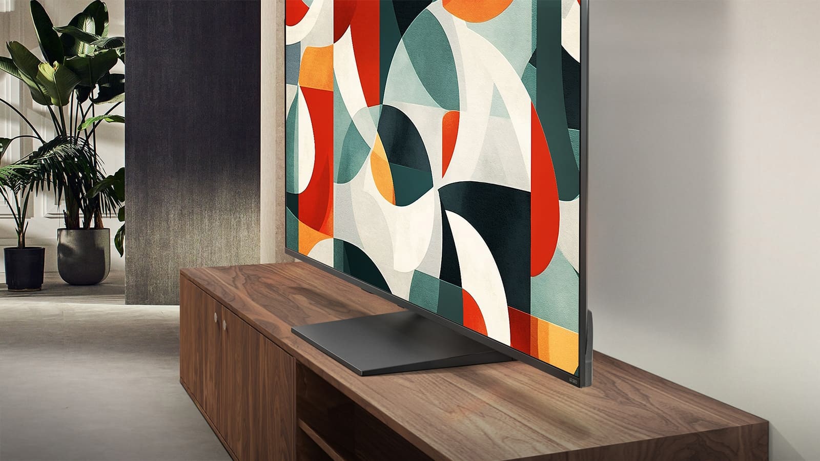 Televizorul LG QNED se află deasupra unui dulap pentru televizor într-un spațiu de living modern. Televizorul LG QNED afișează un fundal abstract în nuanțe de verde, roșu și portocaliu.
