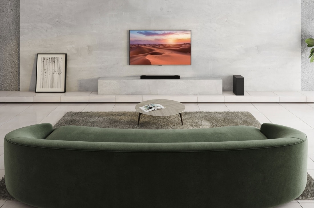 LG Soundbar LG S75Q, O bară de sunet este plasată sub televizor într-o cameră de zi albă, difuzorul spate plasat chiar lângă aceasta, S75Q, thumbnail 4