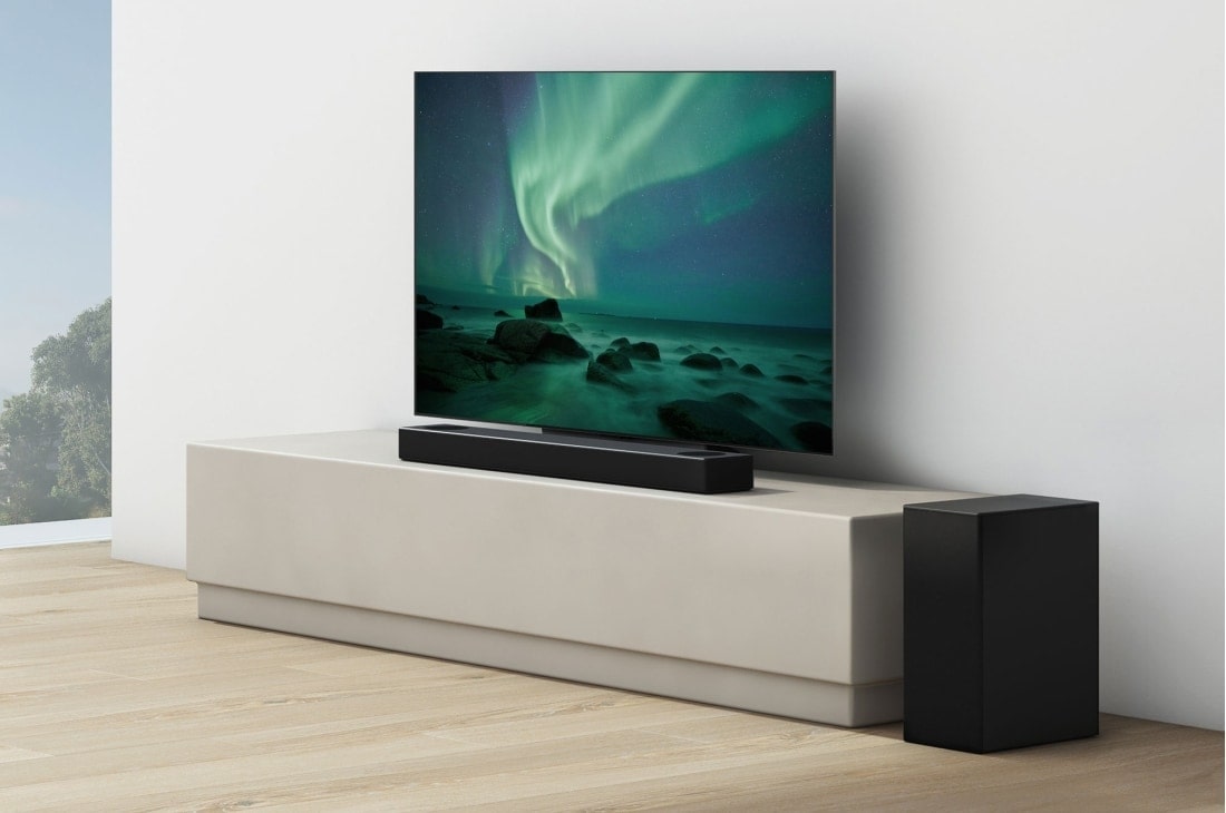 LG Soundbar LG S75Q, O bară de sunet și un televizor sunt plasate pe un raft bej, difuzorul spate plasat chiar lângă acestea, S75Q, thumbnail 5