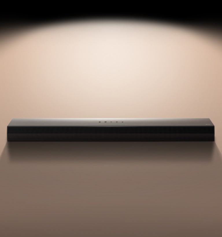 Soundbarul LG, pe un fundal negru, evidențiat de un proiector de lumină.