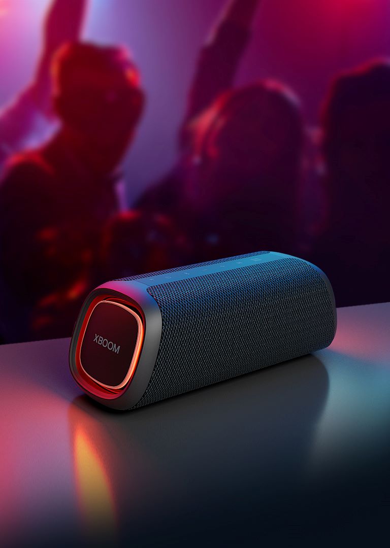 LG XBOOM Go XG7 este plasat pe masa de metal, cu luminile portocalii aprinse.