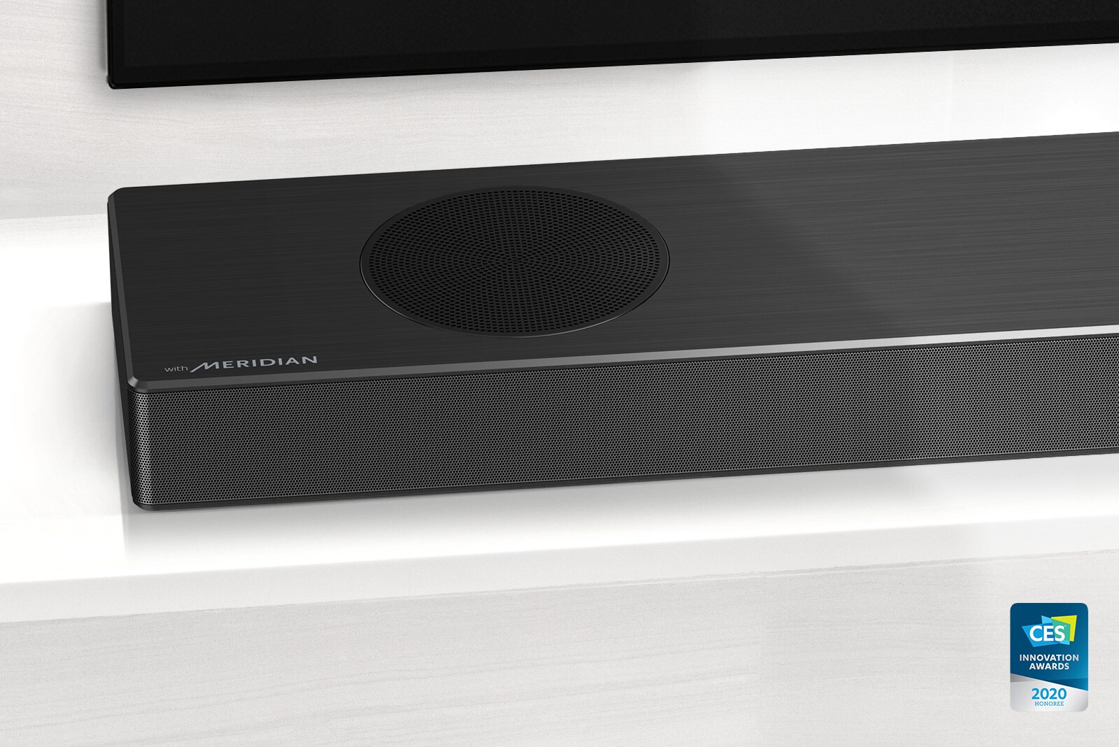Prim-plan cu partea din stânga a soundbar LG, cu logo-ul Meridian afișat în colțul din stânga jos. Partea din stânga jos a televizorului este, de asemenea, vizibilă.
