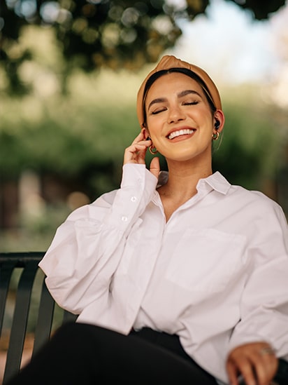Woman wearing TONE Free black and enjoying music with closed eyes in the city