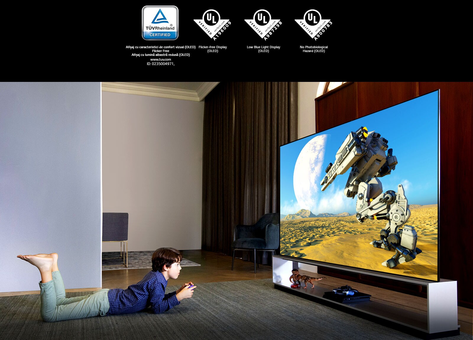 Un băiat care stă întins pe burtă, pe un covoraș, urmărind o animație la un televizor cu lumină albastră estompată, Marcaj TÜV Rheinland / Marcaj Verificare UL 