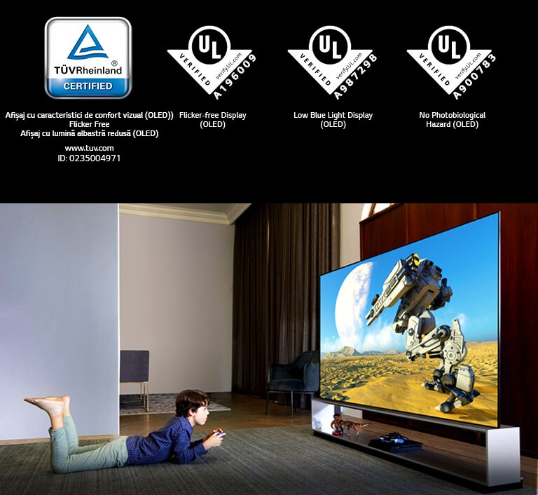 Un băiat care stă întins pe burtă, pe un covoraș, urmărind o animație la un televizor cu lumină albastră estompată, Marcaj TÜV Rheinland / Marcaj Verificare UL 