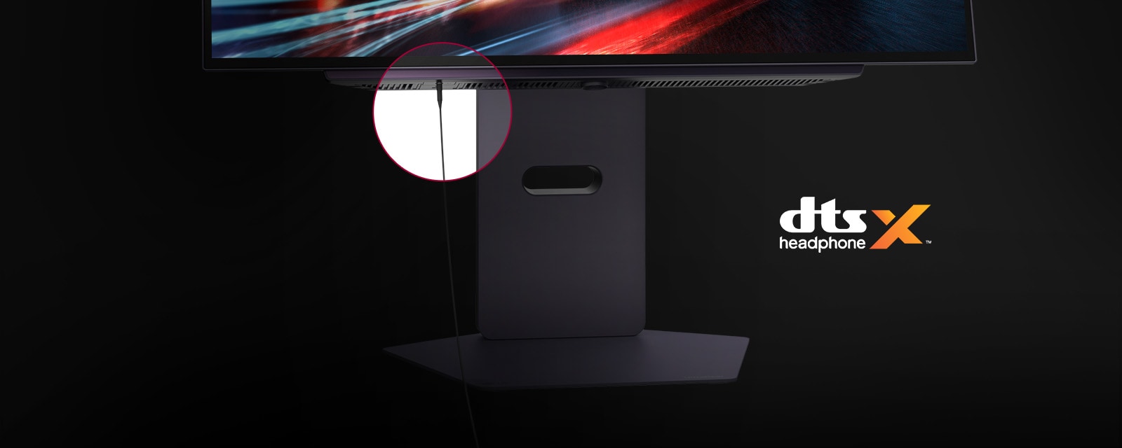 Prim plan al unui suport de monitor cu un cablu de căști conectat și logo DTS Headphone X afișat.	