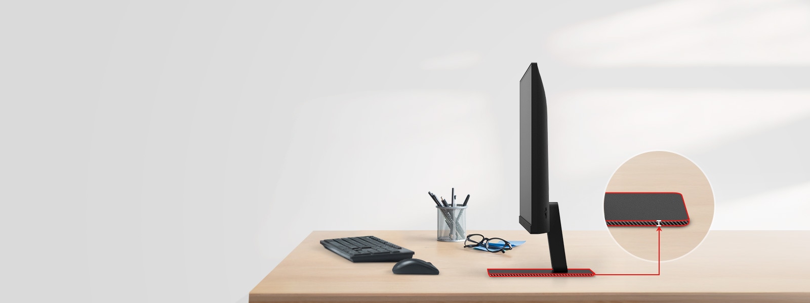 Un monitor QHD cu un suport foarte subțire este pe birou, cu un suport pentru pixuri, ochelari, o tastatură și un mouse alături.