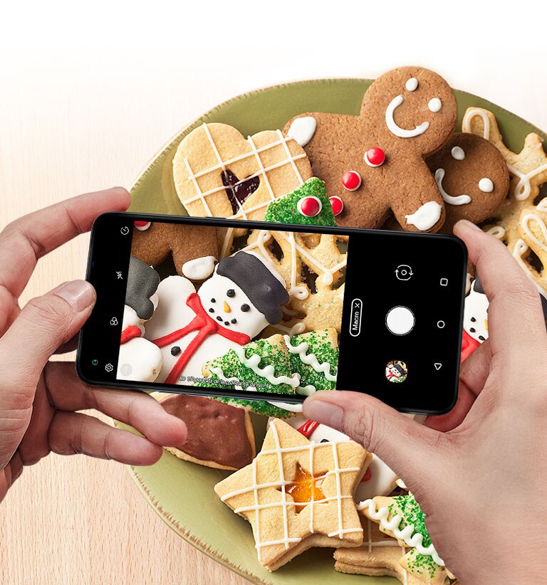 Imagine de aproape a unei persoane care fotografiază prăjituri cu un smartphone.