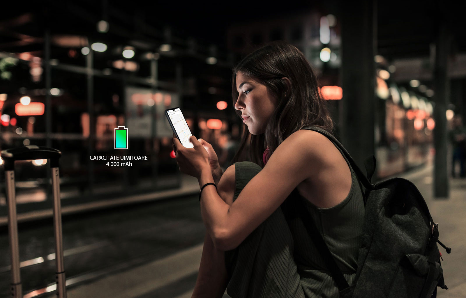 Femeie care caută pe internet de pe telefonul său, care mai are suficientă baterie, noapte târziu, într-o stație de metrou.