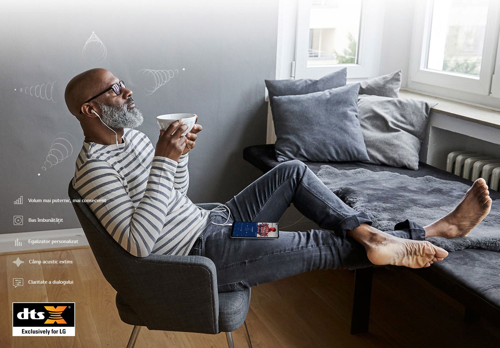 Un bărbat așezat pe un scaun, care bea cafea și asculta muzică în căști