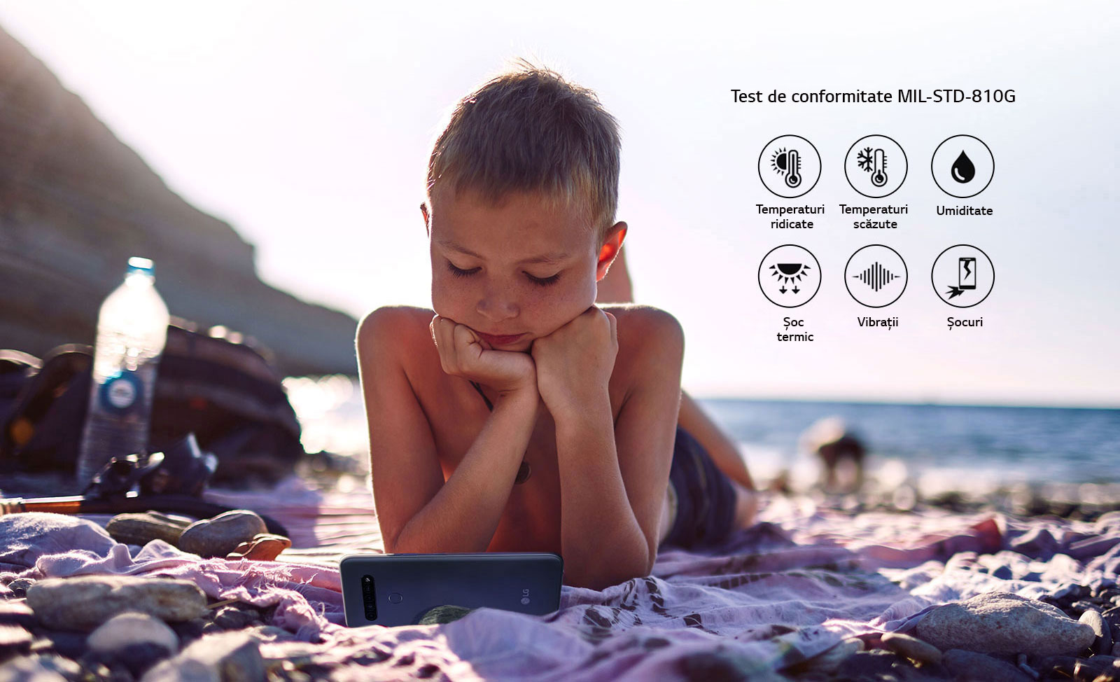 Copil care stă pe plajă și se uită la un film, de pe smarthone-ul său