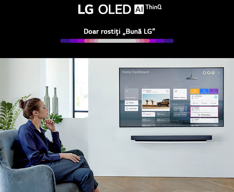 Un bărbat și o femeie care stau pe o canapea în camera de zi, cu Home Dashboard pe ecranul TV