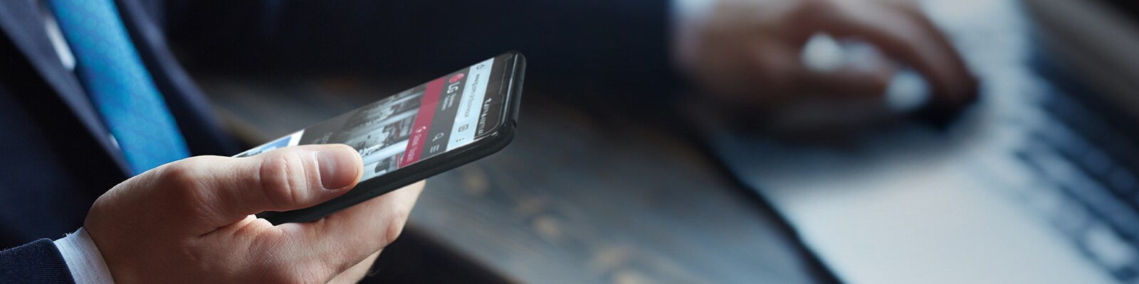 Slika čoveka koji drži pametan telefon sa veb-stranom kompanije LG na ekranu.